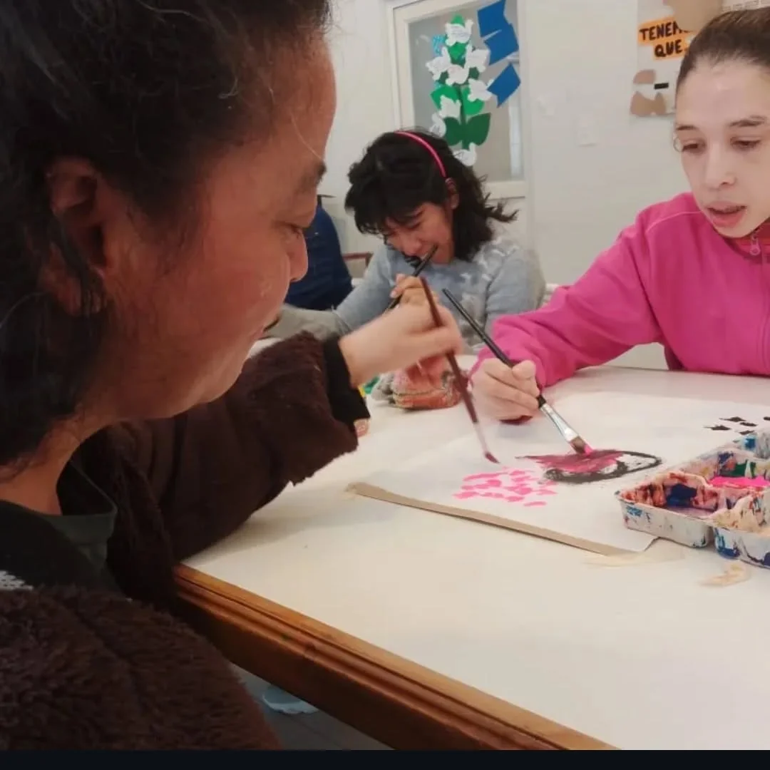 Participantes comparten una mesa con pinturas y pinceles.