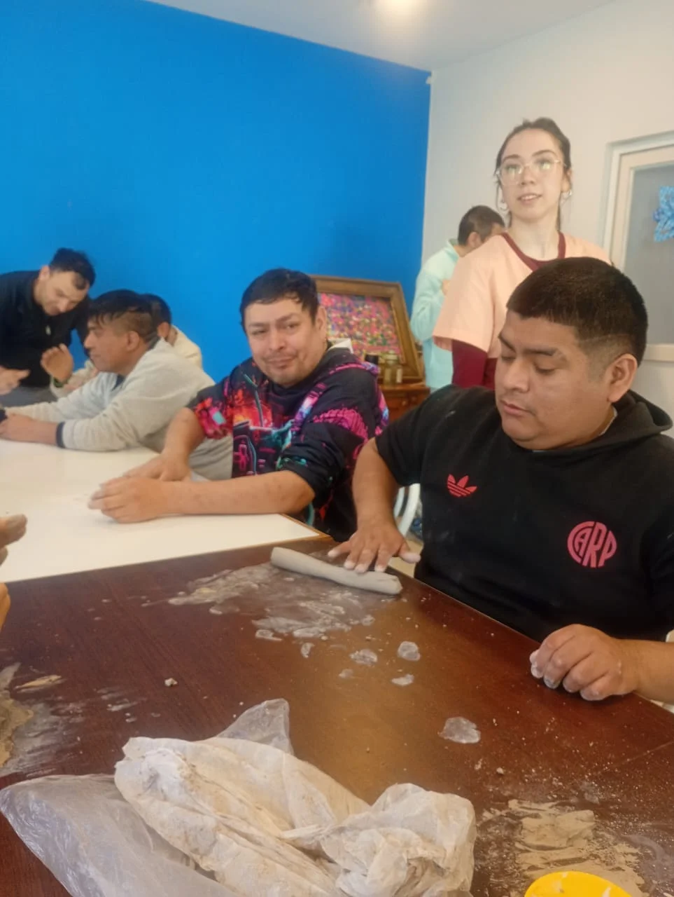 Participantes reunidos alrededor de la mesa del taller de arte.