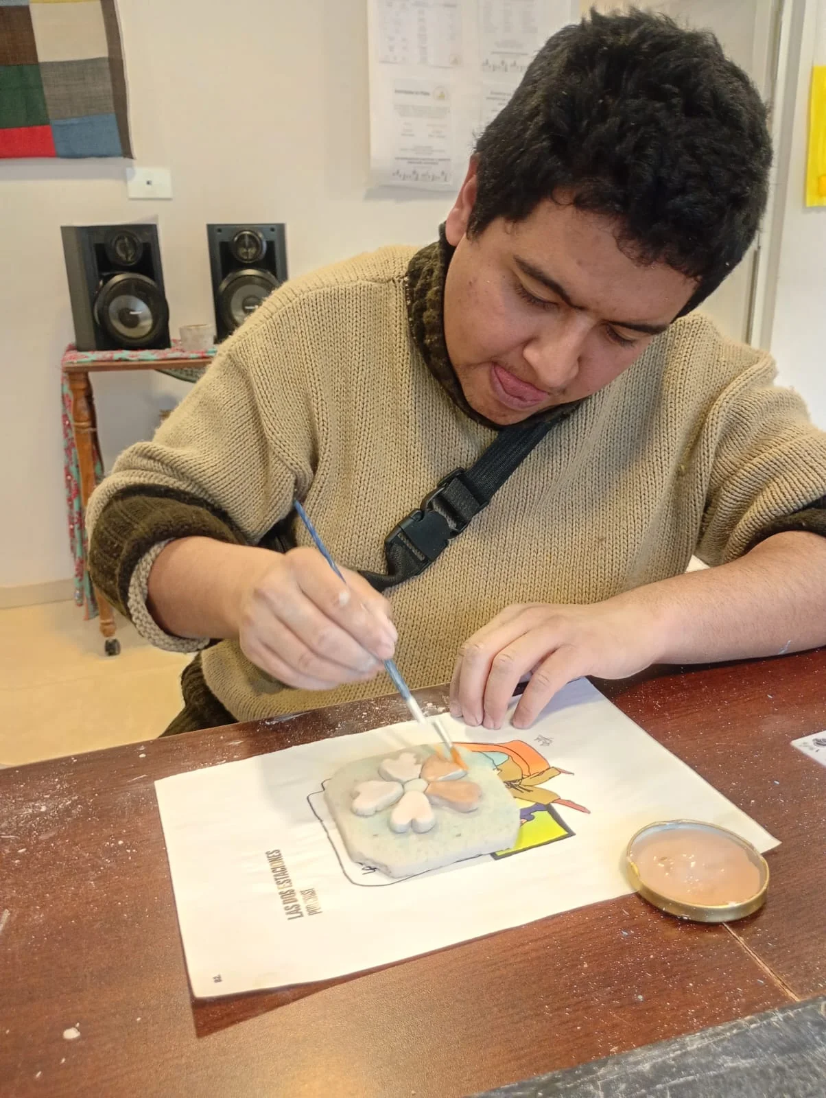 Una participante pinta su trabajo sobre la mesa.