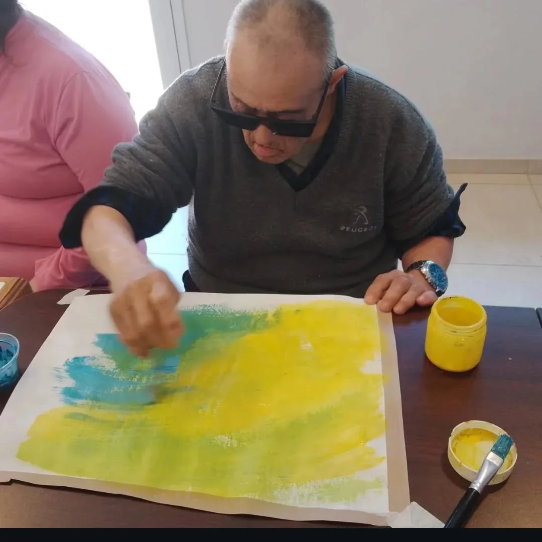 Un participante extiende pintura sobre un trabajo amarillo y azul.