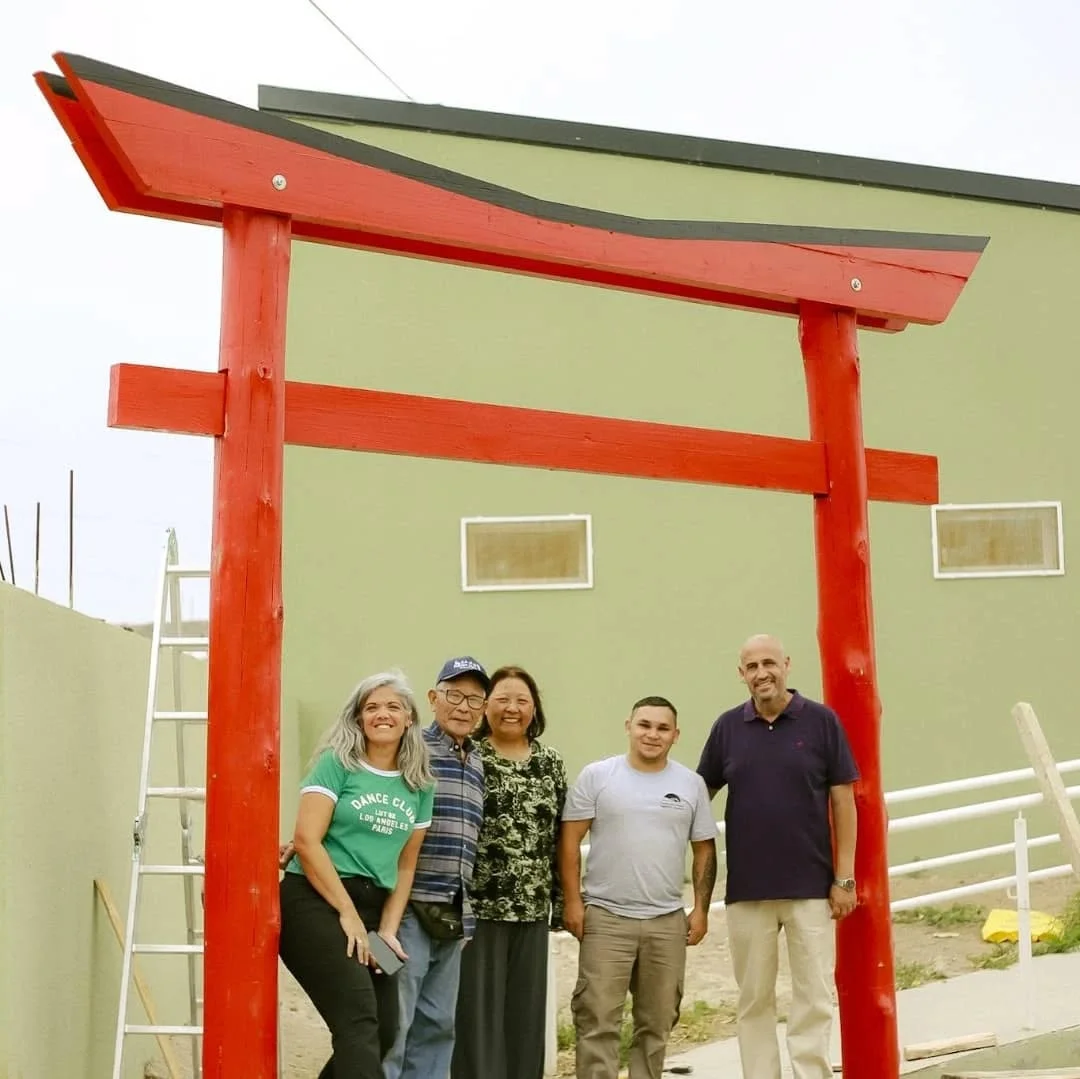 Un grupo de personas frente a la entrada de Casa EDDIM y su pórtico rojo.