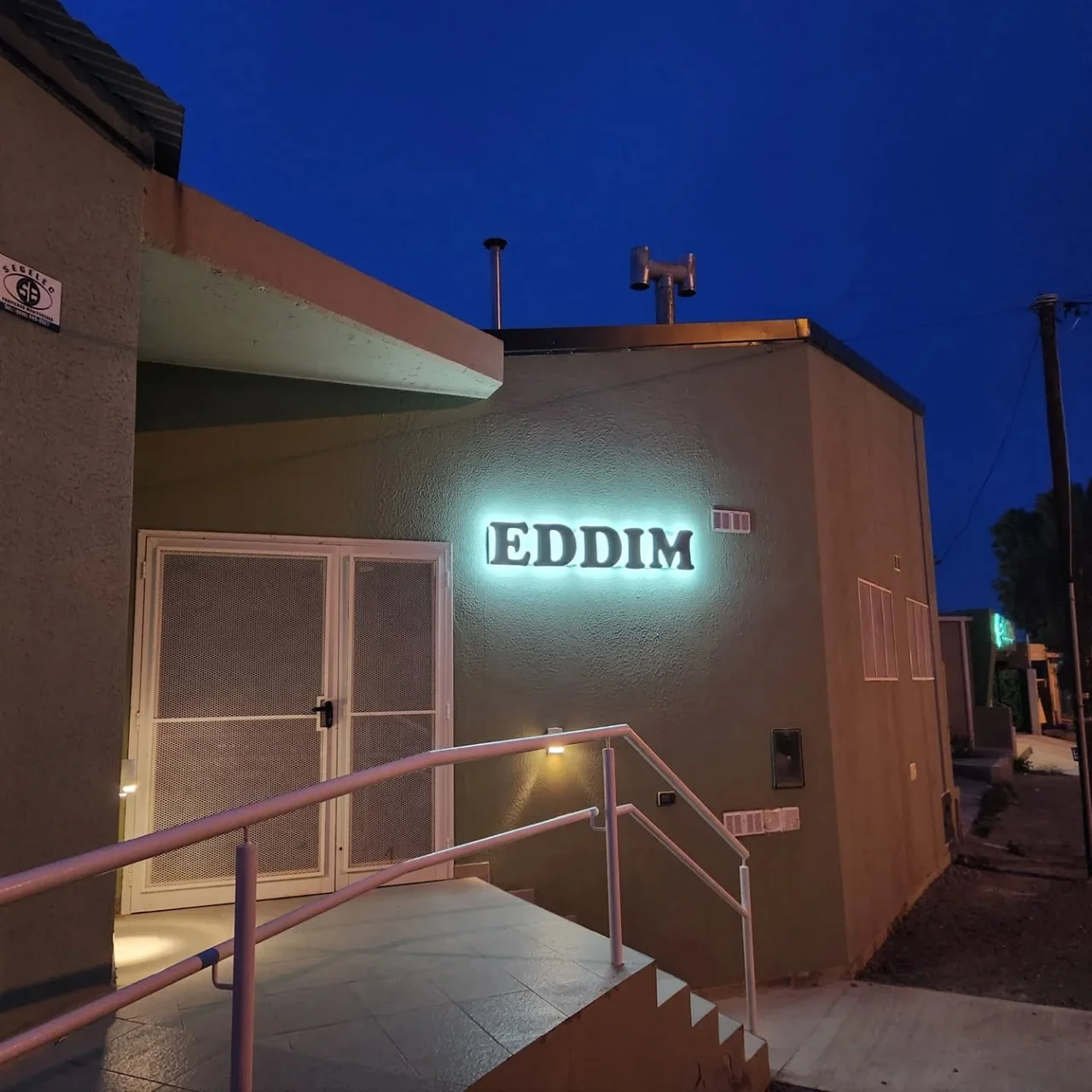 La entrada de Casa EDDIM, con su rampa de acceso y el cartel iluminado.