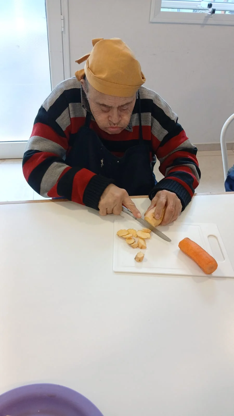 Un participante corta alimentos sobre una tabla en el taller de cocina.