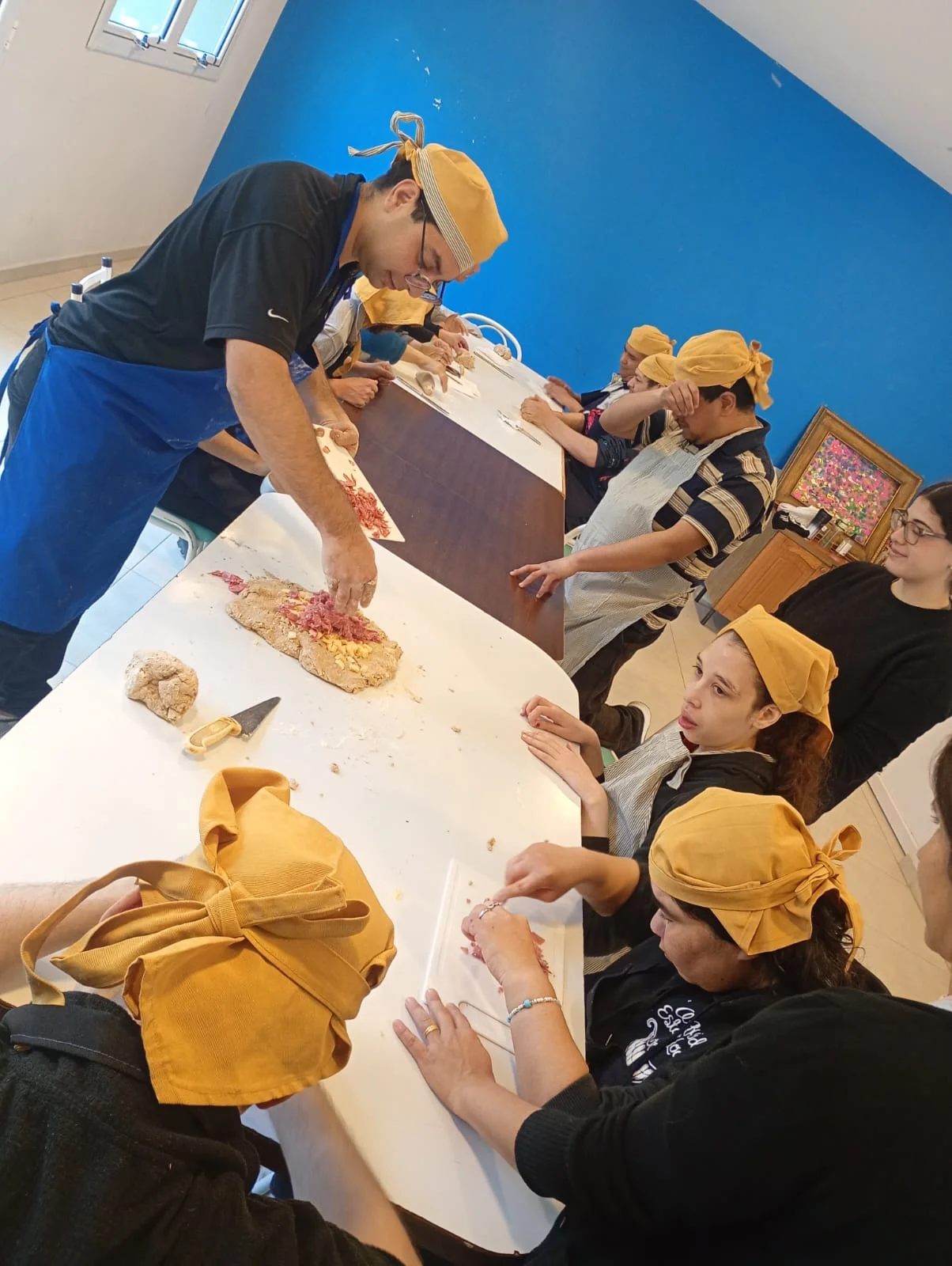 El grupo prepara alimentos con gorros de cocina amarillos.