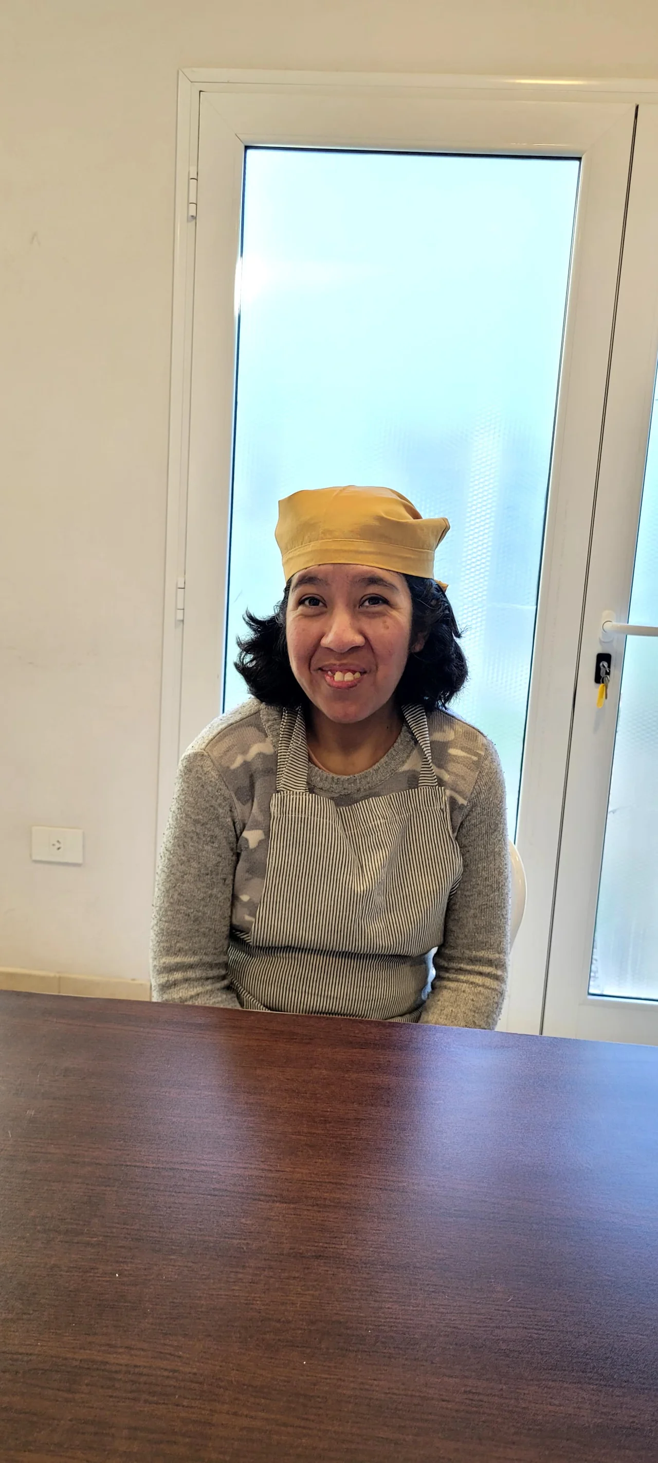 Una participante espera junto a la mesa de trabajo del taller de cocina.