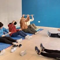 Participantes realizan ejercicios sentados en el suelo.