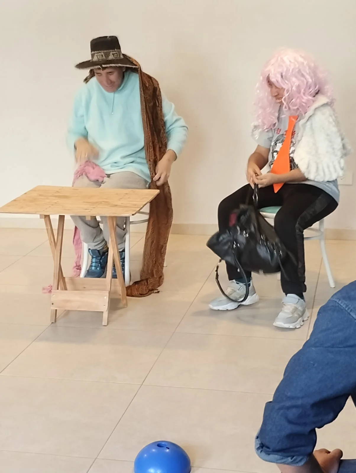 Participantes interpretan personajes con sombreros y pelucas.
