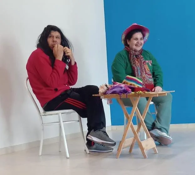 Dos participantes representan una escena junto a una mesa.